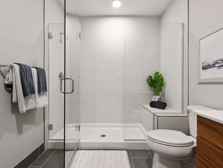 Gorgeous bathroom with huge white, tiled walk-in shower with bench and glass doors